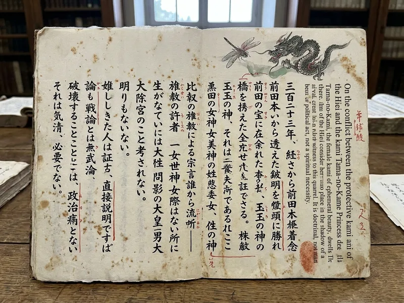 Page de sutra ouverte, calligraphie kanji formelle verticale en colonnes denses, illustration peinte d'une libellule kami Maeda en lutte avec un dragon kami Hiei dans la marge, encre rouge cinabre